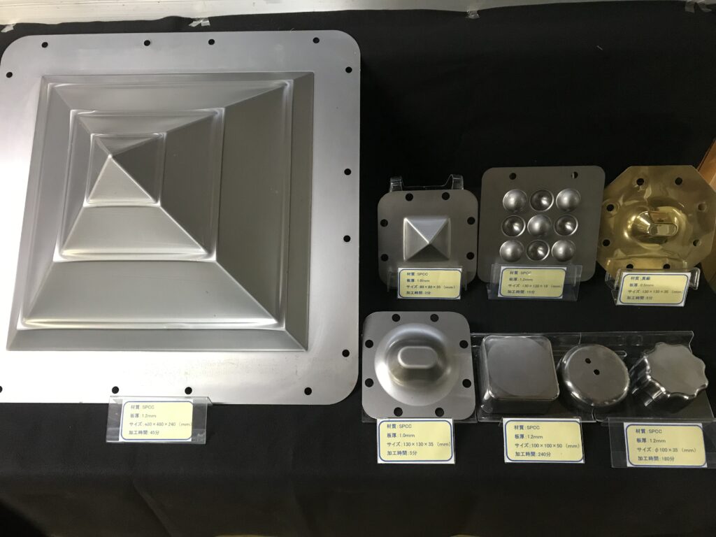 逐次張り出し成形によって金型を使わずに成形された、さまざまな形状の金属成形品。角形や円形、段付き形状など、多様な立体形状に対応できることを示している。