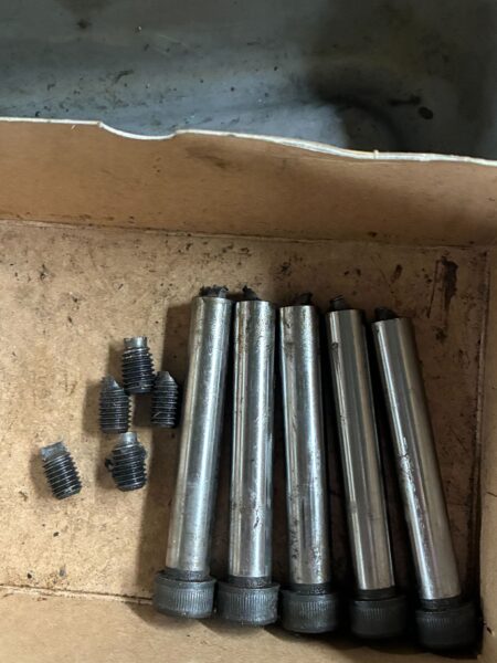 段ボール箱の中に並ぶ5本のストリッパーボルトと、左側に散らばる折れたボルト片4個。ボルト頭部が破断した状態で取り出されている。