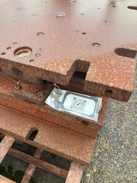 屋外保管されてる金型にチップロックにいれたQRコードを貼り付けてる様子