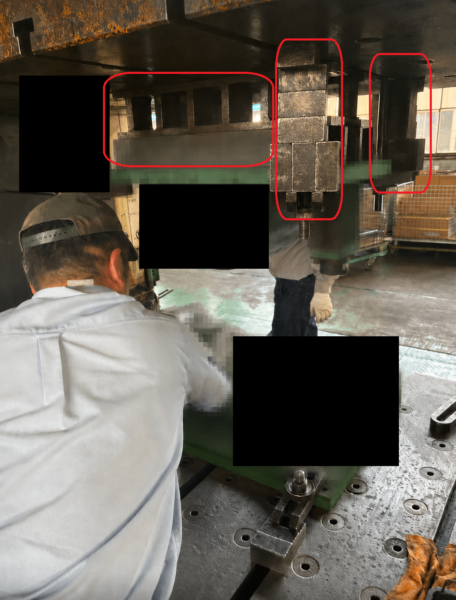 プレス機のスライドと金型の間に金属のブロックを複数枚噛ませ、ダイハイトを合わせながら上型を取り付けている作業の様子